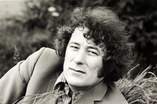 A portrait of Seamus Heaney, with him reclining in a field 