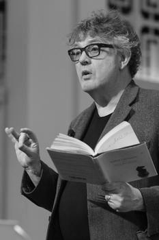 Paul Muldoon with a book in his left hand at a poetry reading